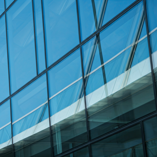 Clean minimal architectural detail of a glass building reflecting sky and structural beams